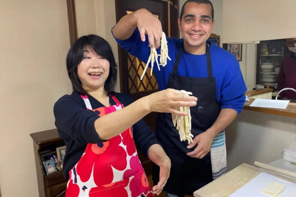 Local teacher and guest proudly holding fresh handmade noodles at a Tokyo udon making class