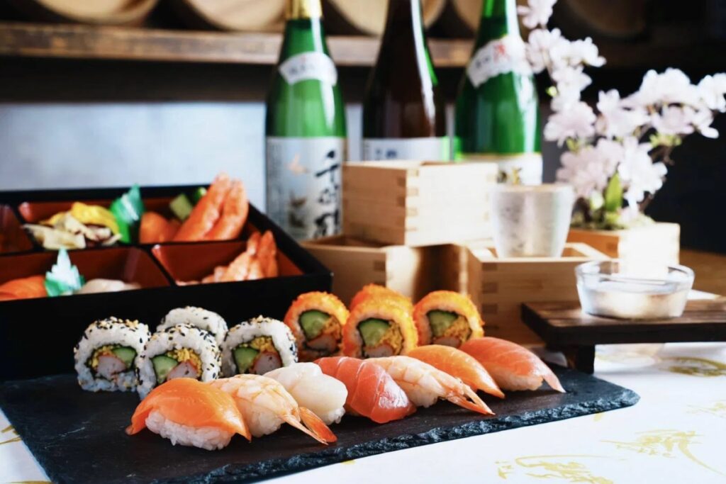 Freshly made nigiri and maki sushi platter with sake bottles at an Asakusa sushi studio in Tokyo