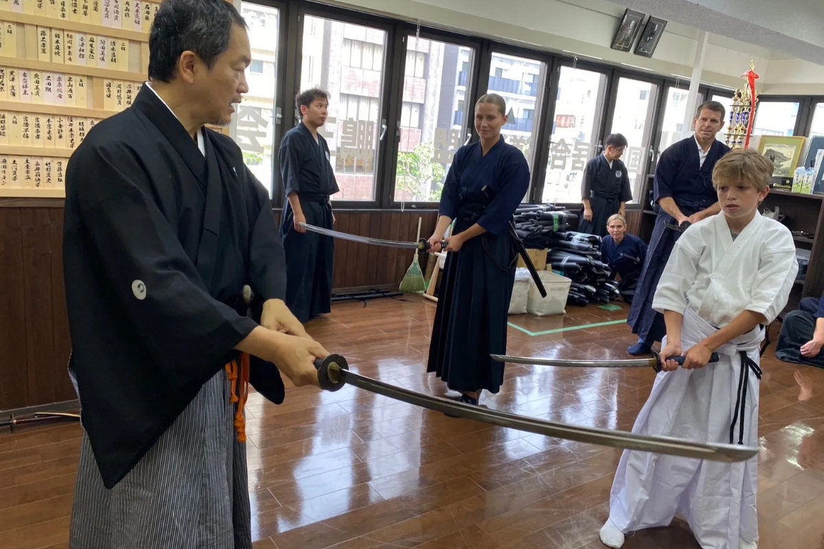 Iaido master guiding a young guest in samurai sword movements during a Tokyo Iaido experience
