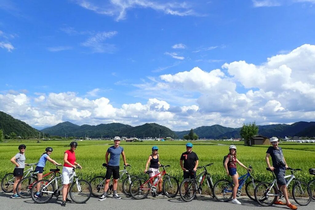 group of tourists posing with their mountain bikes against a backdrop of clear blue skies on the Hida Furukawa Bike Tour.