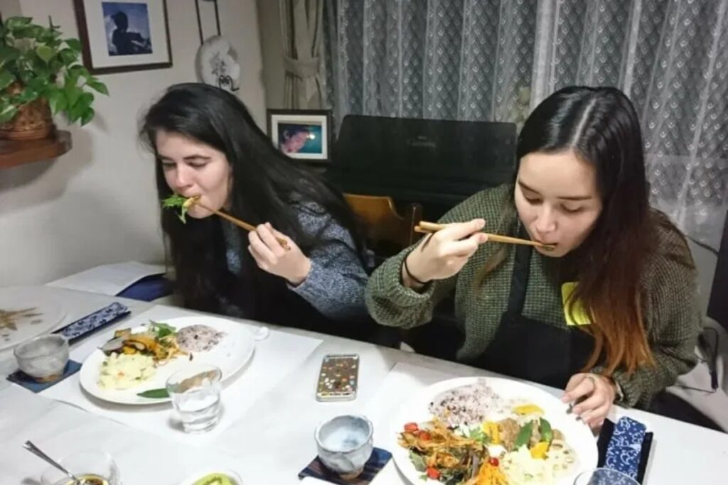 International guests enjoying their home-cooked vegan Japanese meal with chopsticks in Tokyo