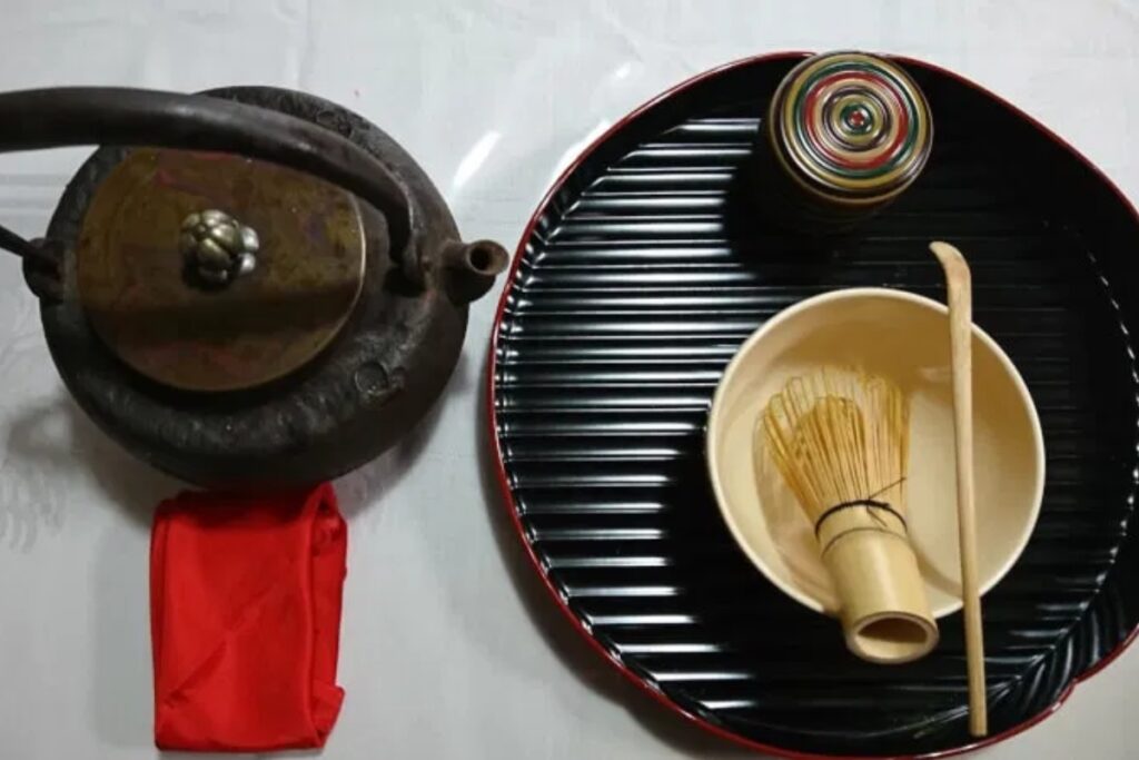 Traditional Japanese matcha tea set with iron kettle, bamboo whisk, and lacquer tray for the tea ceremony