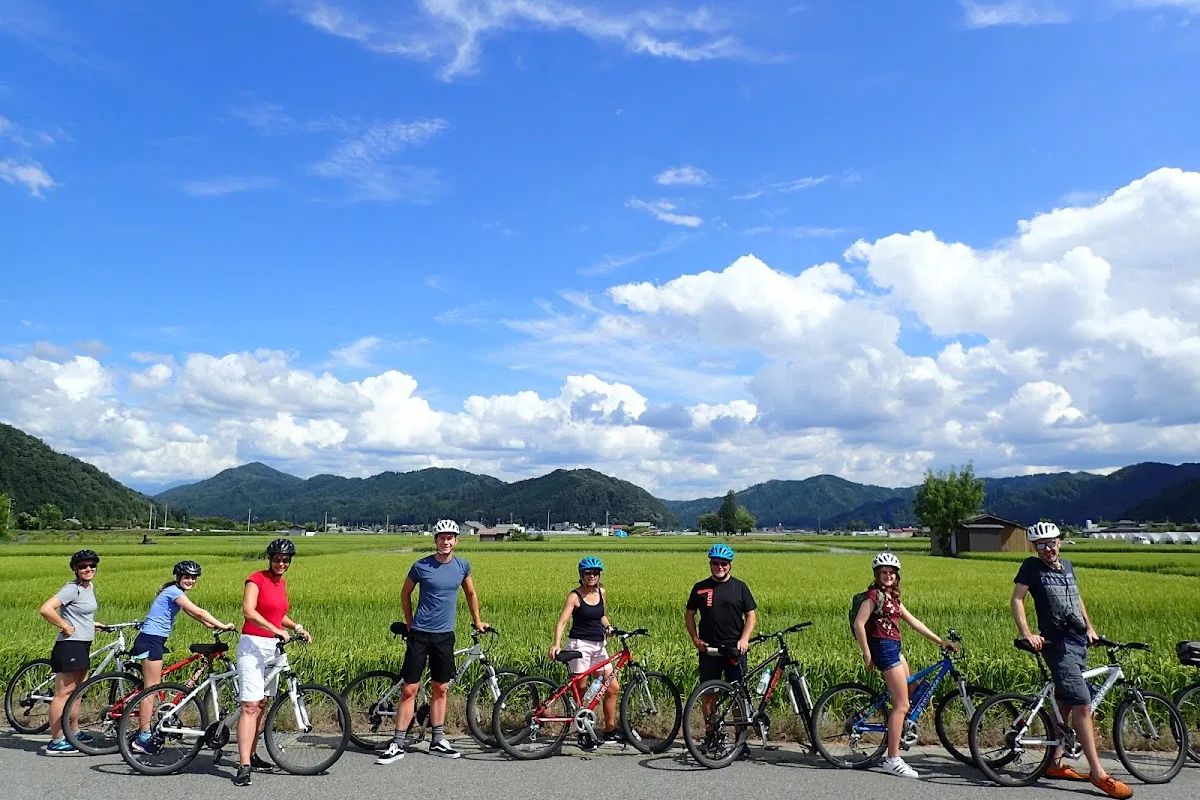 group of tourists posing with their mountain bikes against a backdrop of clear blue skies on the Hida Furukawa Bike Tour.
