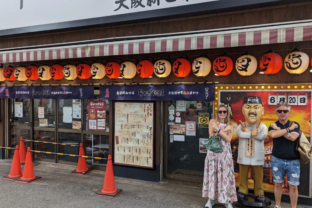 A woman smiling outside a traditional Japanese restaurant decorated with red lanterns.