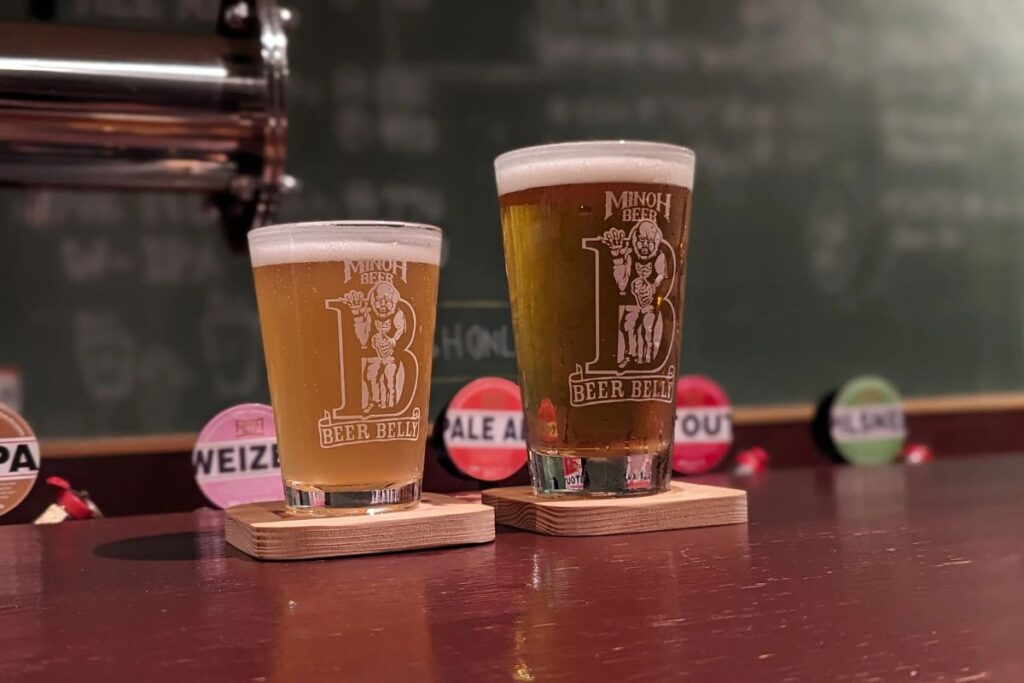 Two frosty glasses of local craft beer sitting on a wooden bar counter.