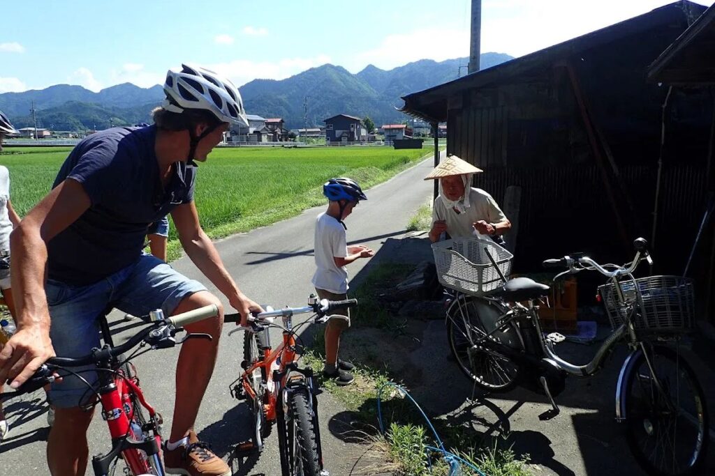A friendly local guide interacting with a young cyclist in rural Japan.