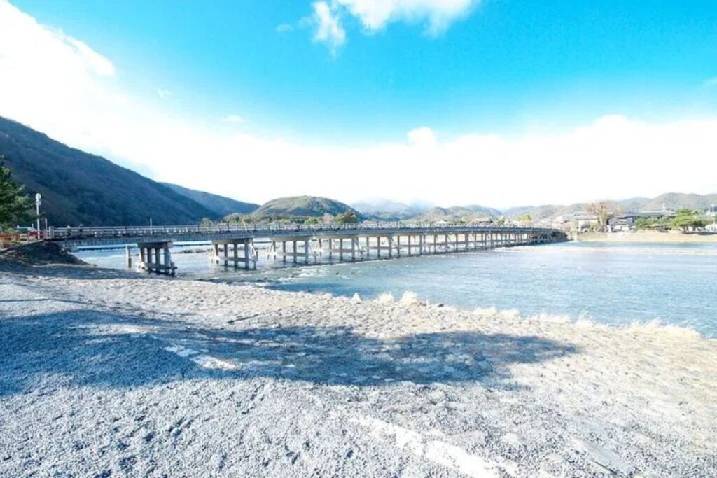 A wide scenic view of a majestic bridge crossing a beautiful river on a private arashiyama walking tour.