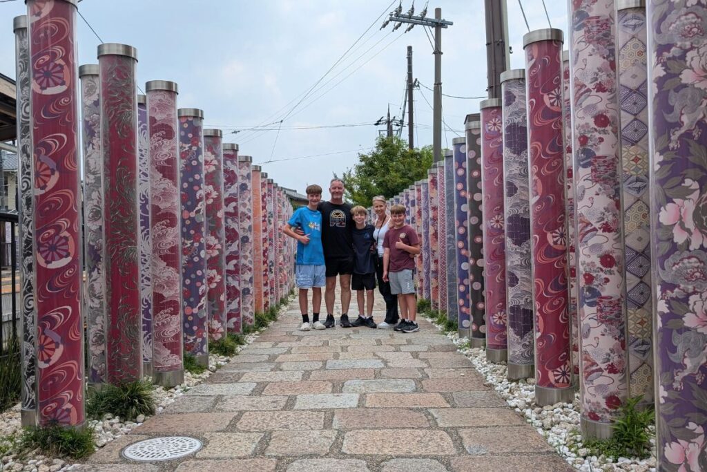 Five people standing together on a stone path lined with beautiful illuminated fabric pillars.
