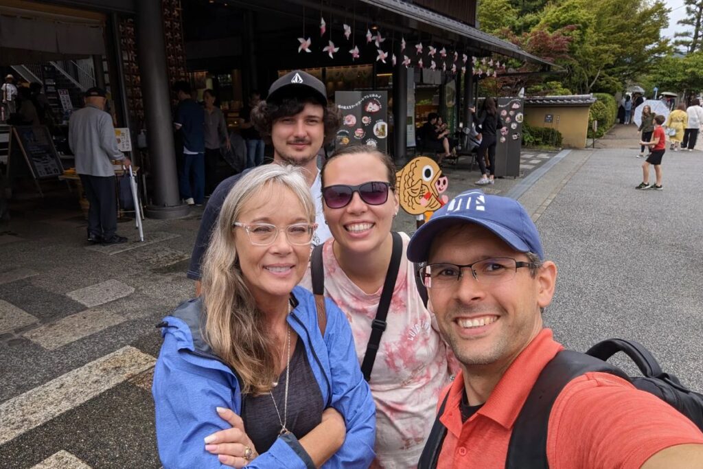 A group of four friends taking a happy selfie on a lively traditional shopping street.