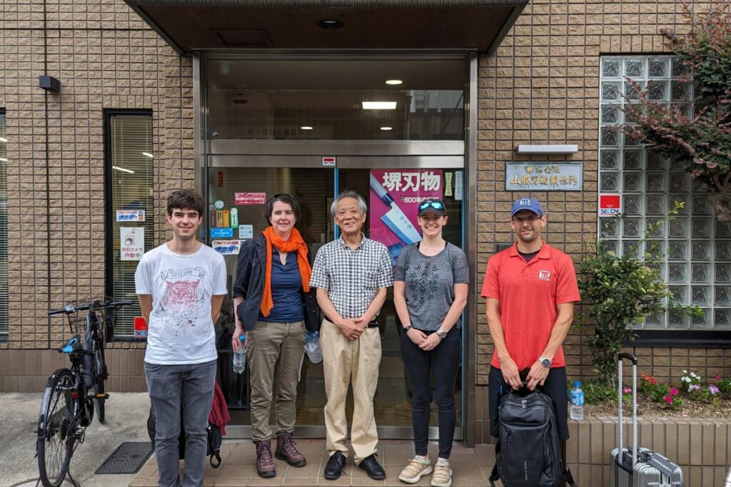 A group of travelers posing outside a traditional factory during a private sakai knife tour.