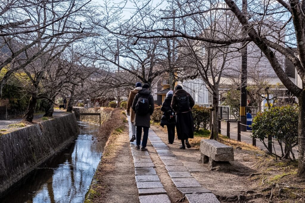 A private group strolling along the historic stone path next to the canal on the Philosopher’s Path during a Kyoto private culture tour.