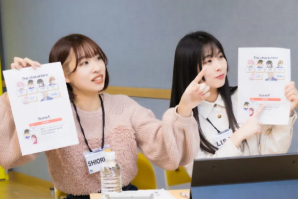 The voice acting instructors leads an enthusiastic group of guests holding scripts during an animation voice-acting workshop in a studio.
