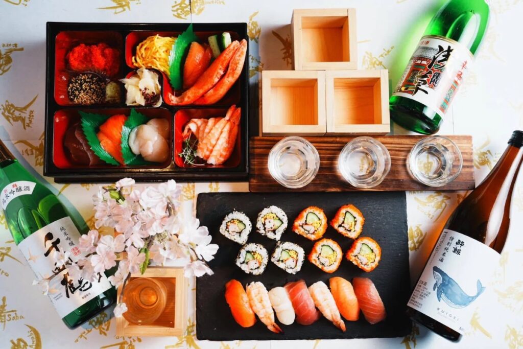 Overhead view of handmade sushi, sashimi box, and sake flight at a Tokyo sushi making experience