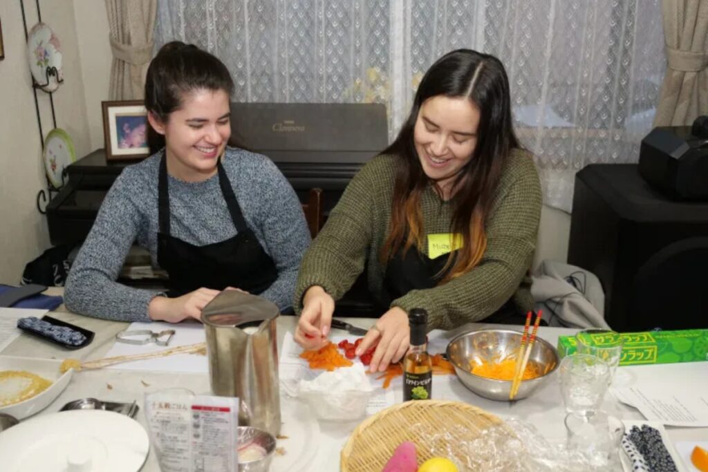 Two international guests laughing while preparing vegetables at a Tokyo vegan cooking class