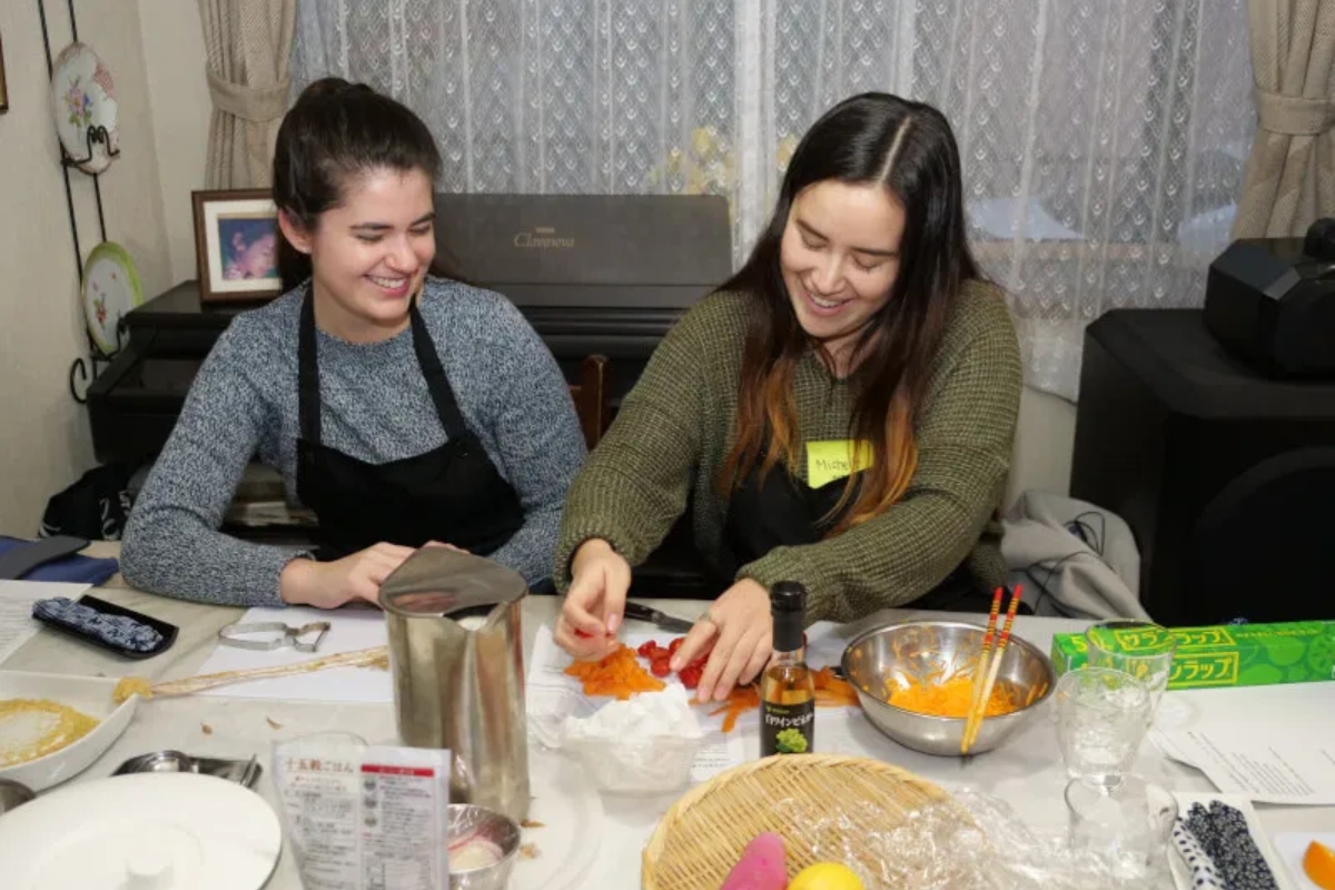 Two international guests laughing while preparing vegetables at a Tokyo vegan cooking class