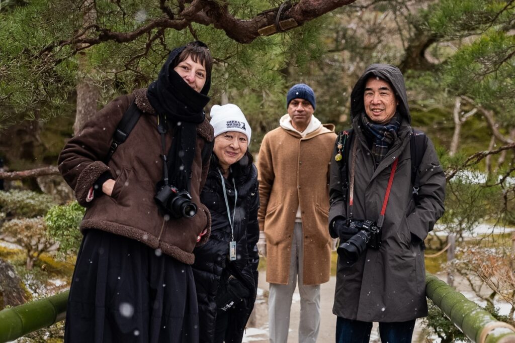 Happy international travelers and their expert local guide smiling during a light snowfall on an authentic Kyoto private culture tour.