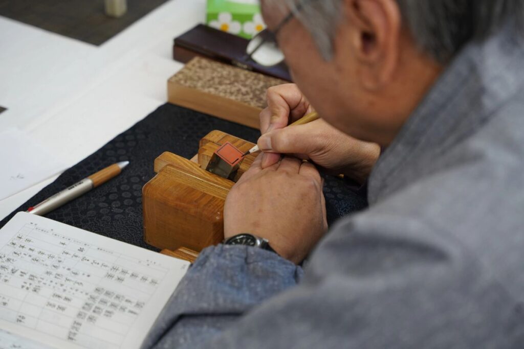 The detailed hands of a master craftsman precision-carving a stone stamp