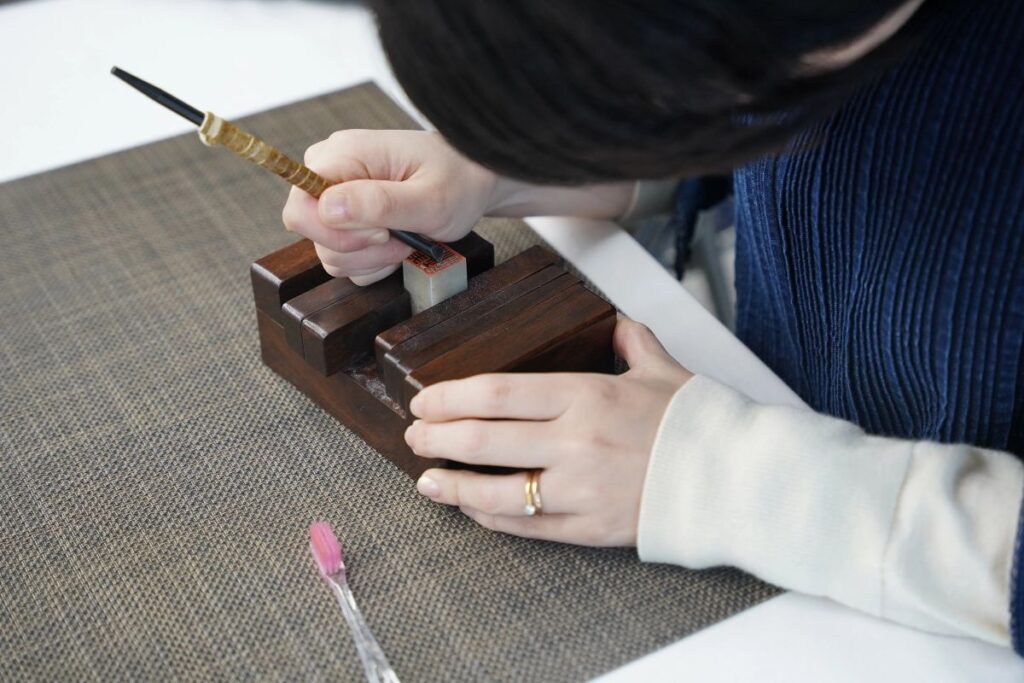 A workshop participant carefully engraving their personalized kanji seal during the premium Artisan Experience Yamanashi.
