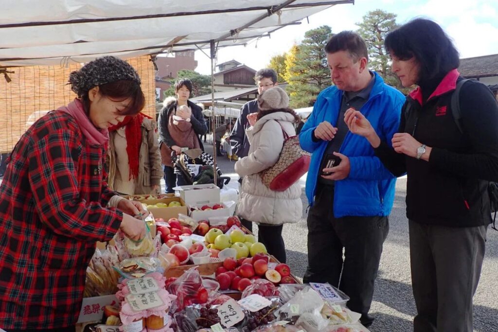 Travelers exploring fresh regional produce at a vibrant morning market in historic Takayama.