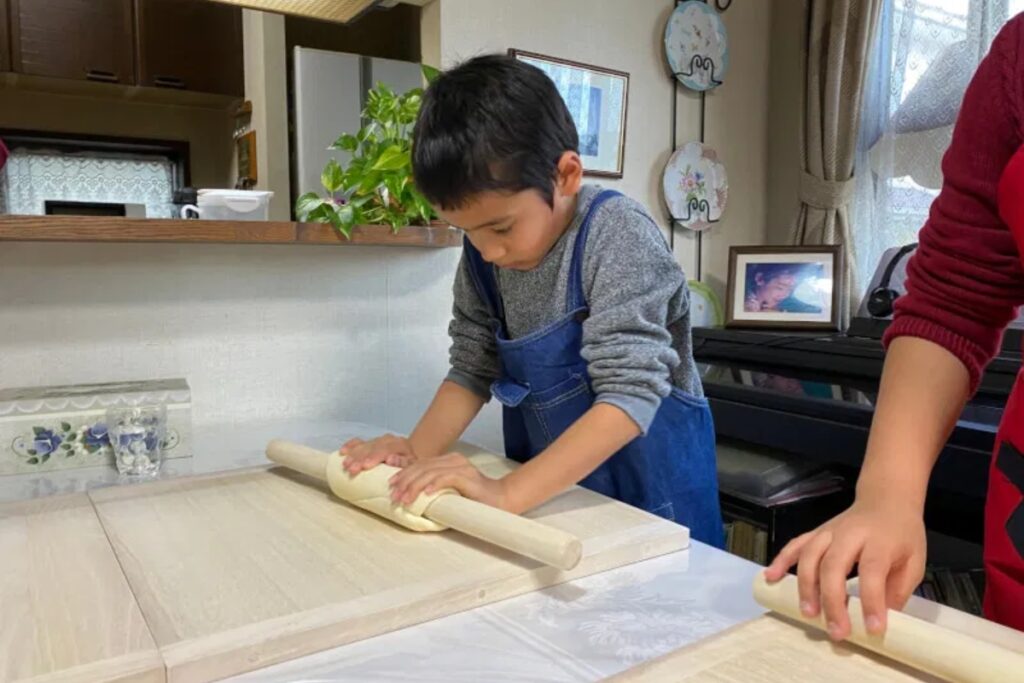 Young guest rolling out udon dough with a wooden pin during a family-friendly Tokyo udon making class
