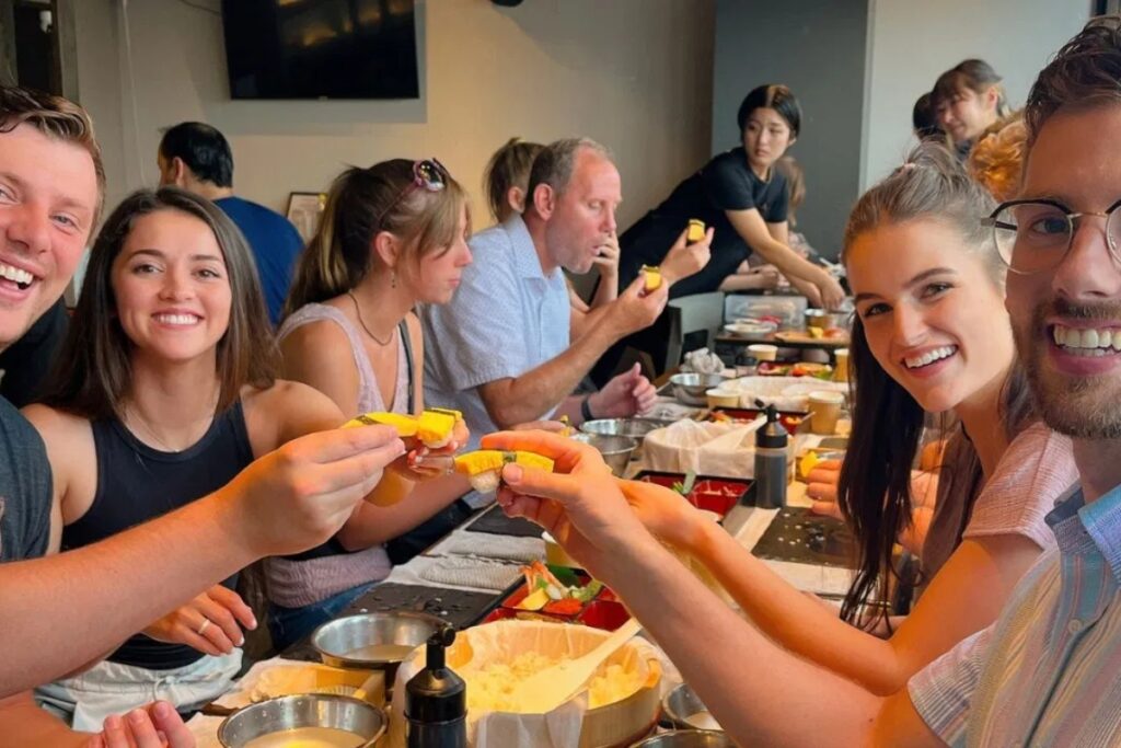 Group of happy guests toasting with their handmade nigiri at a Tokyo sushi making experience