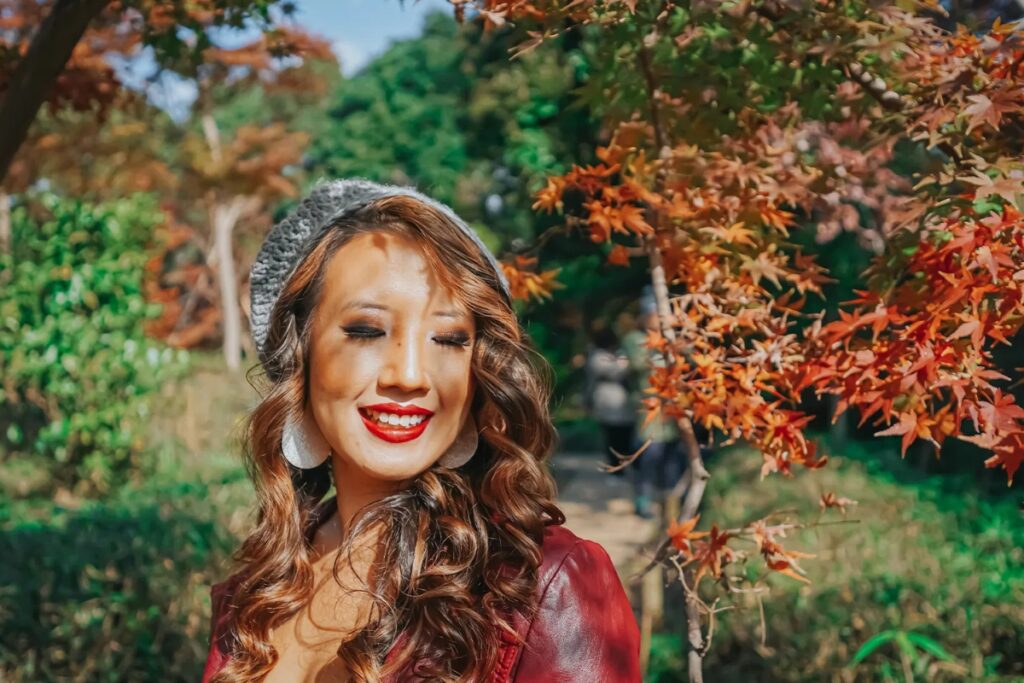 Smiling woman in a red beret photographed among autumn foliage during a Tokyo photoshoot walk