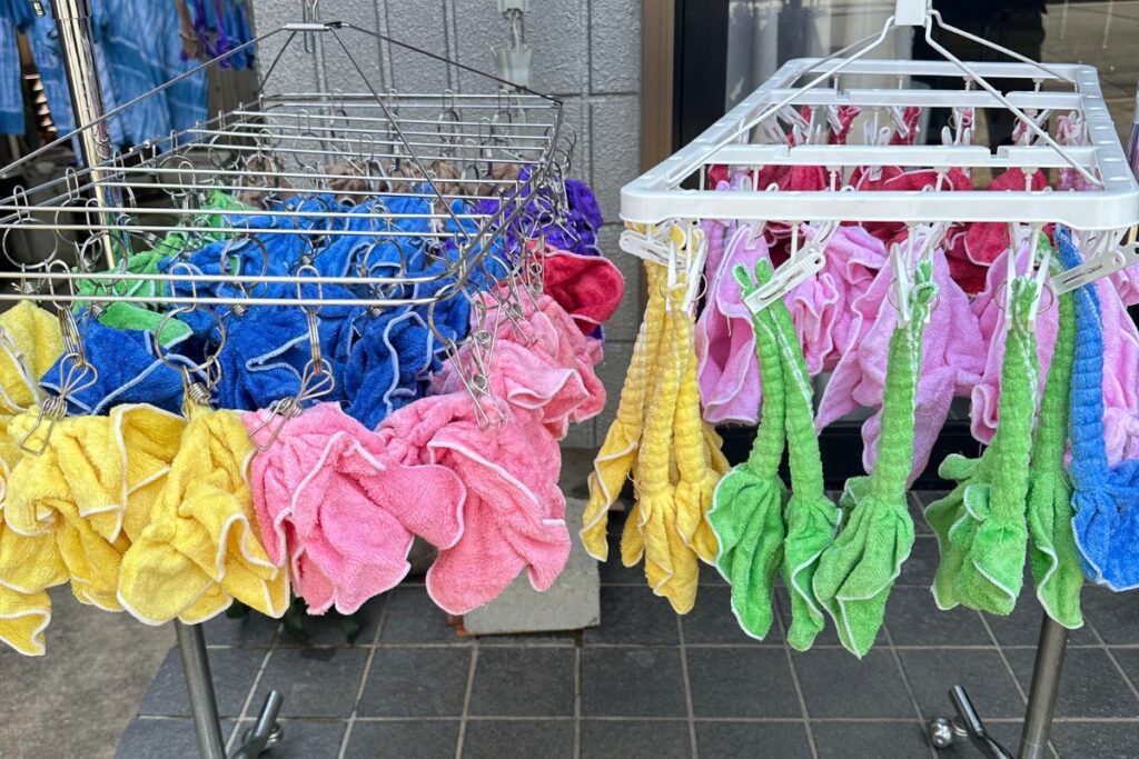 Brightly colored pink, yellow, and green towels drying on a rack after a hands-on fabric binding workshop.