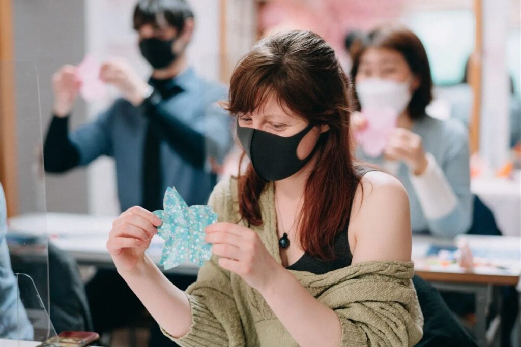 An international traveler concentrating on crafting a beautiful floral cherry blossom pattern during a hands-on Tokyo origami private workshop.