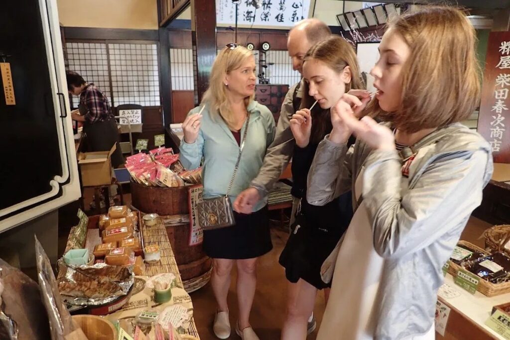 A local guide showing guests traditional Japanese shops and crafts during a Takayama cultural walk.