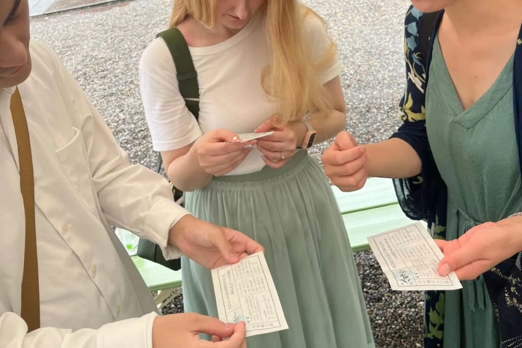 International guests reading their omikuji fortune slips at a Tokyo shrine with a local guide