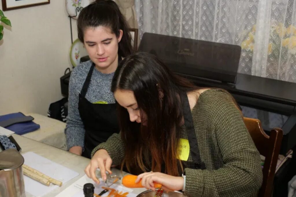 Guests carefully carving carrot garnishes for plant-based dishes during a Tokyo vegan cooking class