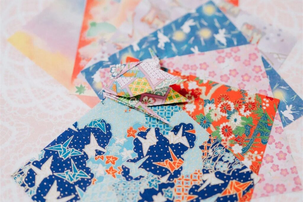 A collection of authentic, colorful Washi paper sheets with a completed traditional paper crane centered during a Tokyo origami private workshop.