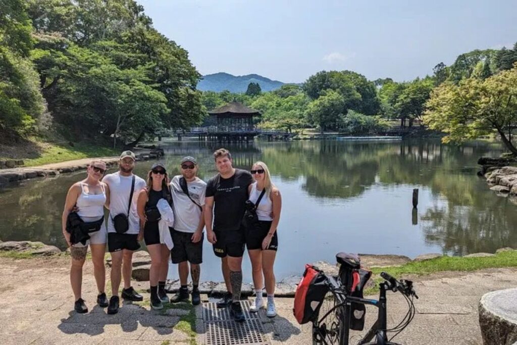 Tour participants pausing together along the edge of a scenic park pond.