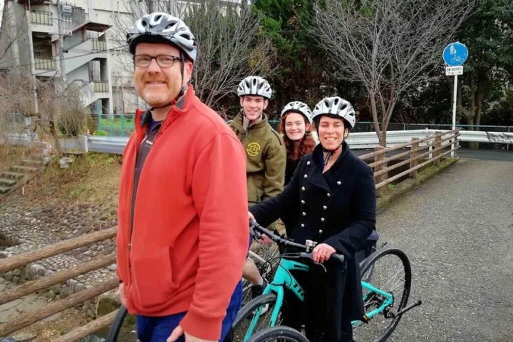 Smiling travelers wearing protective safety helmets while standing outdoors.