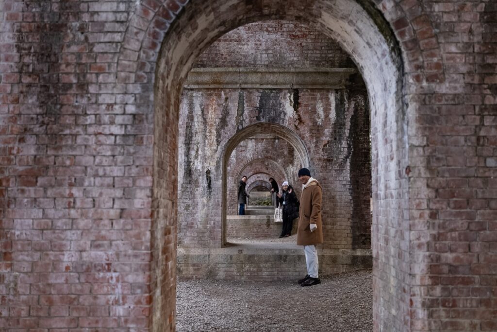Travelers admiring the historic 19th-century red brick aqueduct (Suirokaku) inside temple grounds during a guided Kyoto private culture tour.