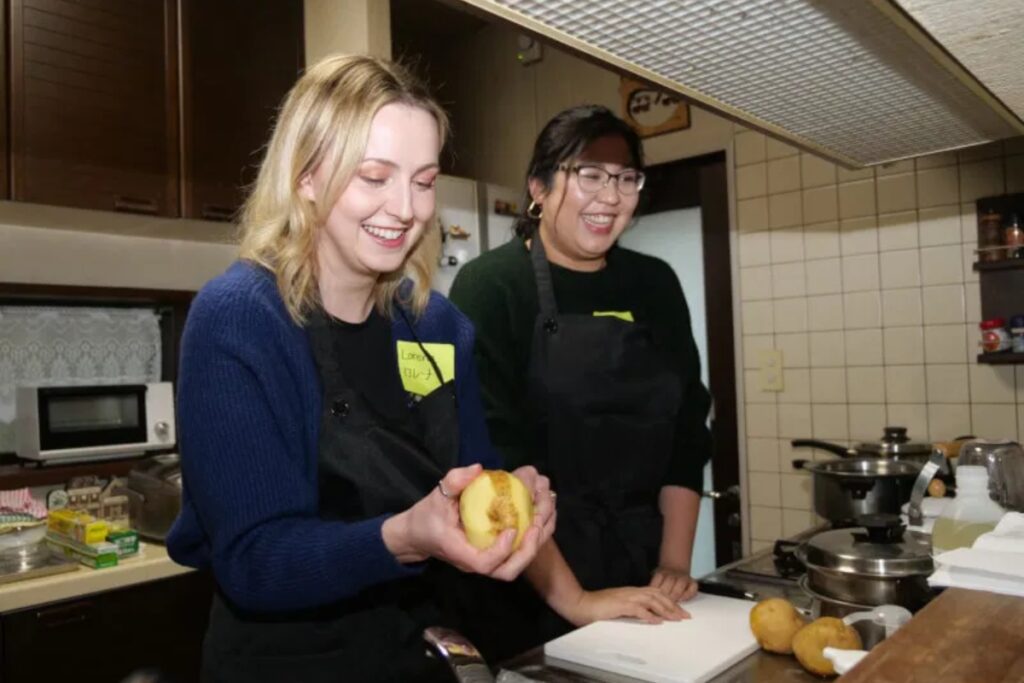 International guest peeling potatoes with her teacher for tofu mayonnaise salad in a Tokyo home