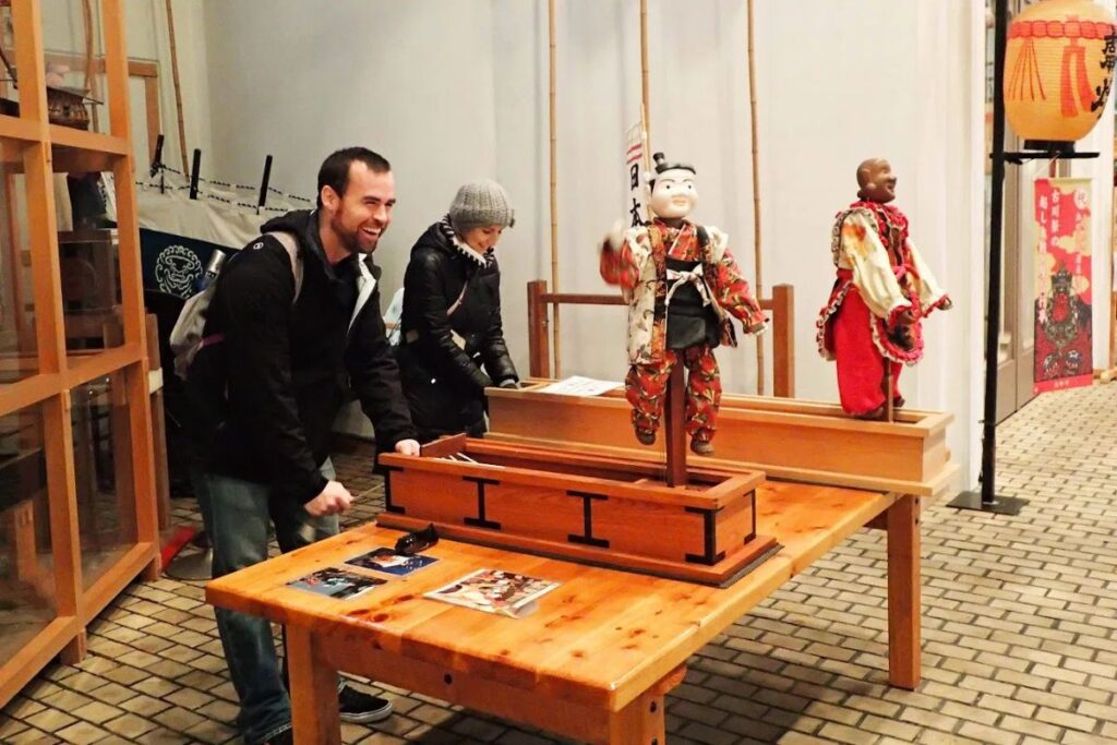 Visitors interacting with cultural exhibits and traditional artifacts inside the town's festival museum.