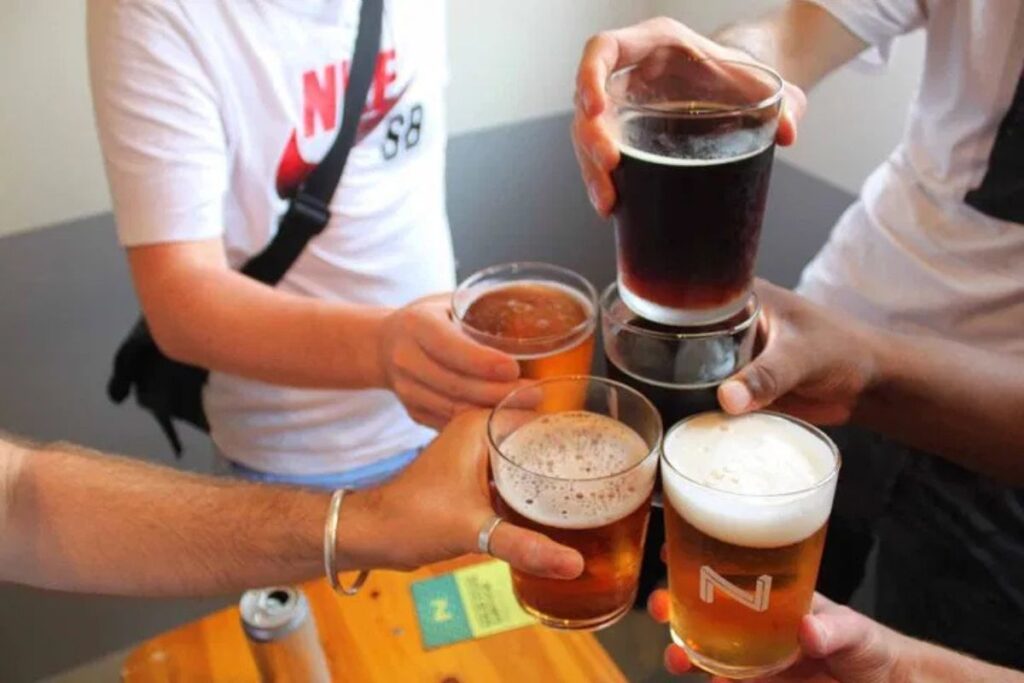 Friends raising foaming glasses of refreshing local craft beer inside a modern microbrewery.