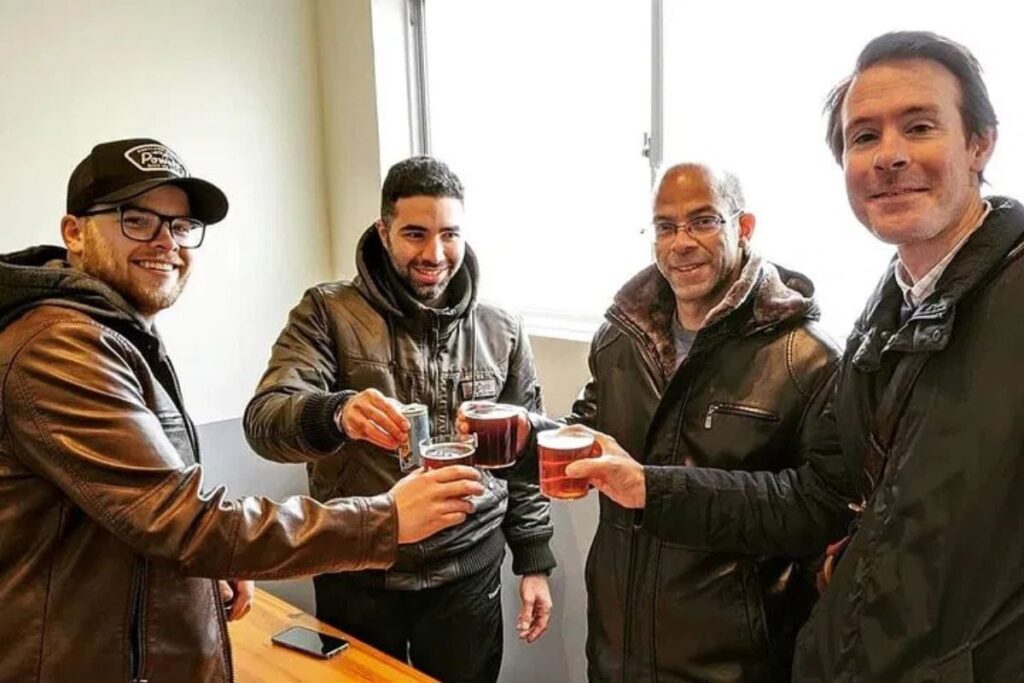 Guests clinking small traditional cups together inside a historic microbrewery.