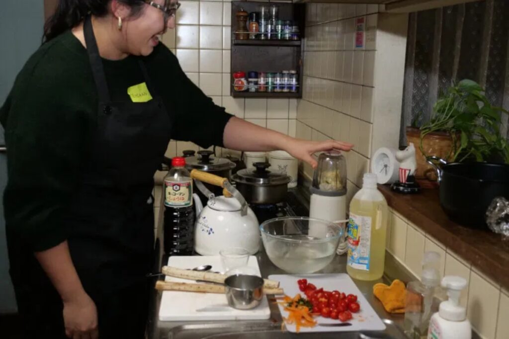 Friendly local teacher preparing cherry tomatoes and vegetables in a cozy Japanese home kitchen