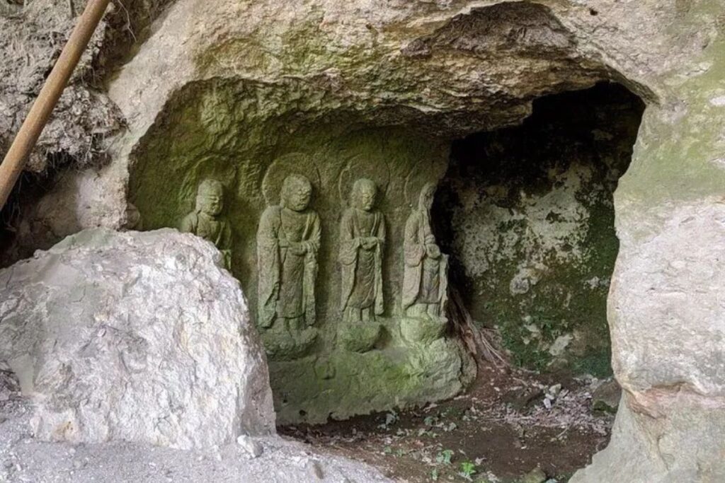 Historic Buddhist figures carved directly into a mossy stone rock face.