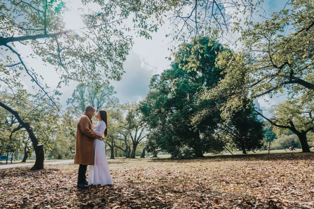 Couple embracing under tall trees in a Tokyo park during a pre-wedding photoshoot walk