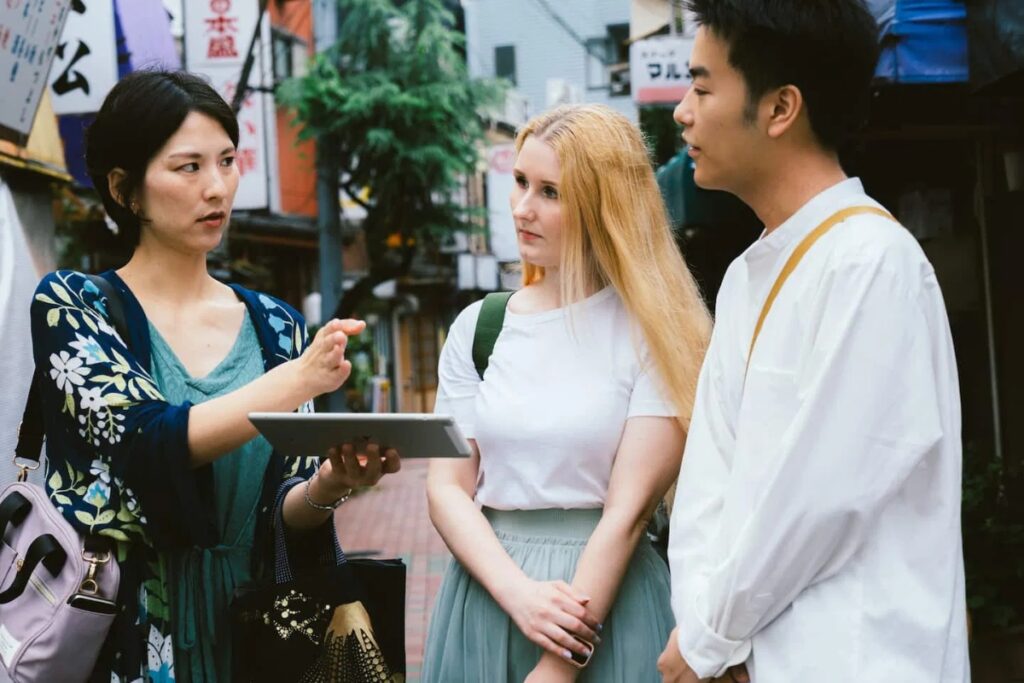 Local guide using a tablet to explain Monzennakacho's history to guests on a Tokyo cultural tour