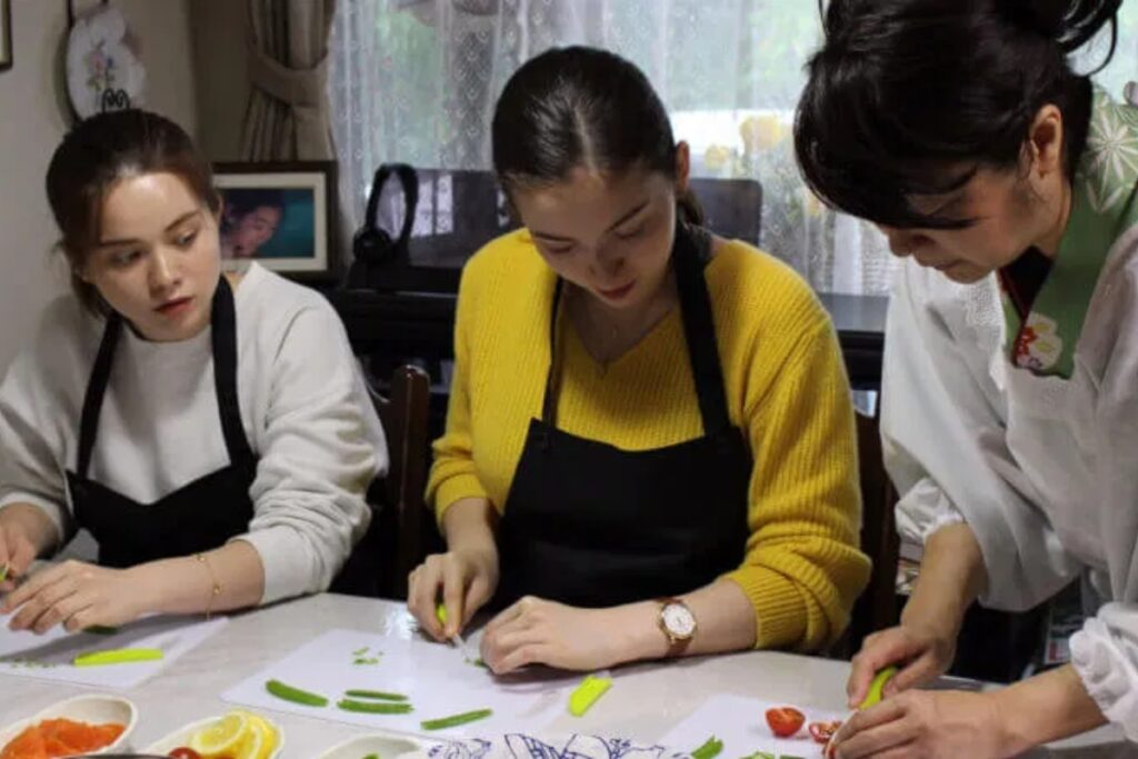 International guest learning to mix sushi rice with her Japanese teacher during a Tokyo sushi cooking class