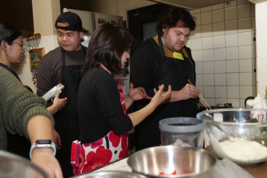Group of international guests cooking together with their host during a Tokyo vegan cooking class