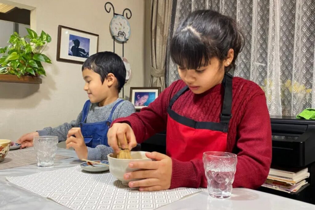 Young guest whisking matcha green tea during the casual tea ceremony at a Tokyo udon making class
