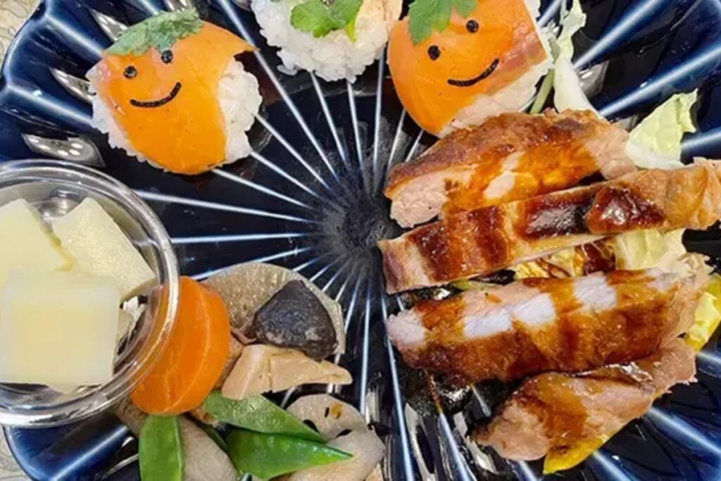 Playful smiling temari sushi and teriyaki on a black plate at a family-friendly Nagoya cooking class