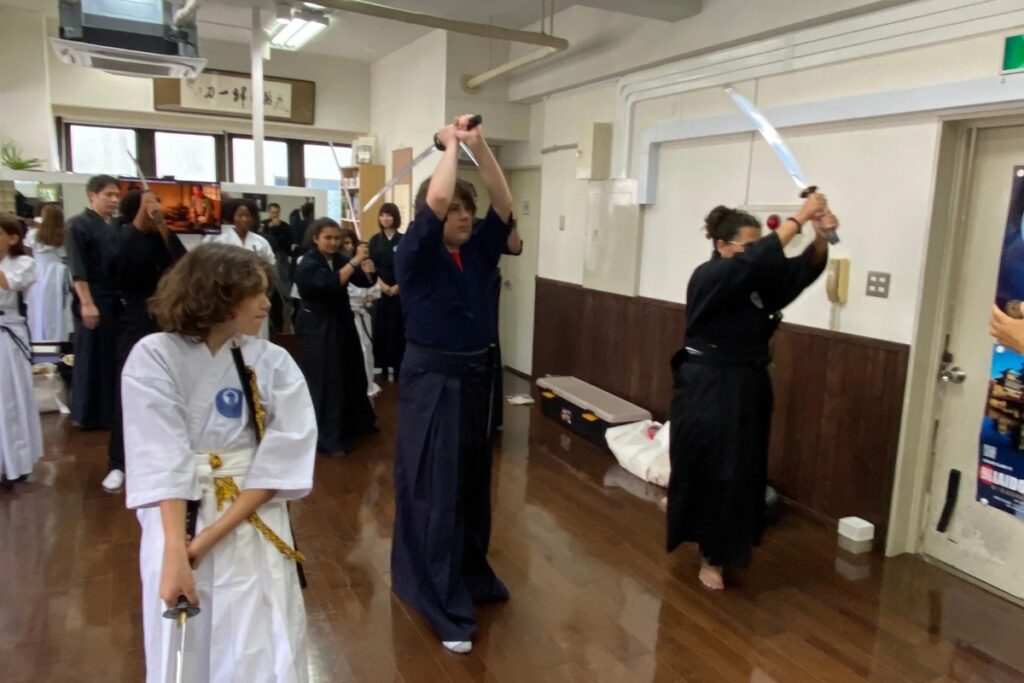 Guests raising their swords overhead while practicing cutting form at a Tokyo Iaido experience