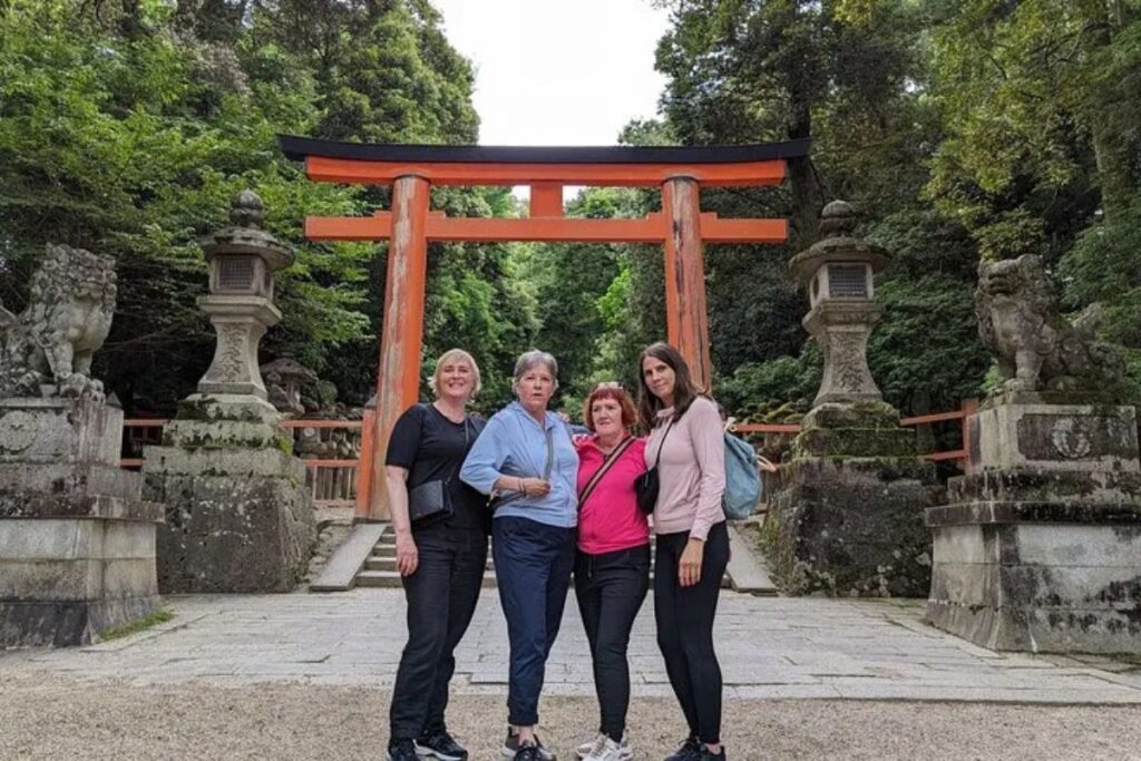 Travelers posing together in front of a majestic red Shinto gate.