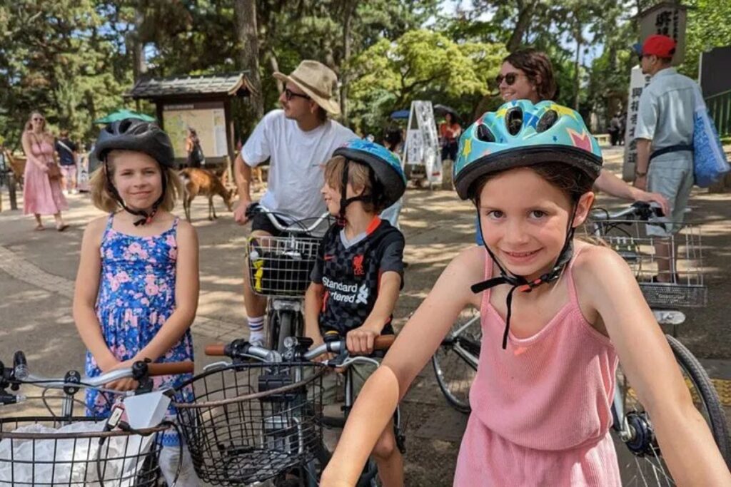 Young riders wearing protective safety helmets and smiling outdoors.